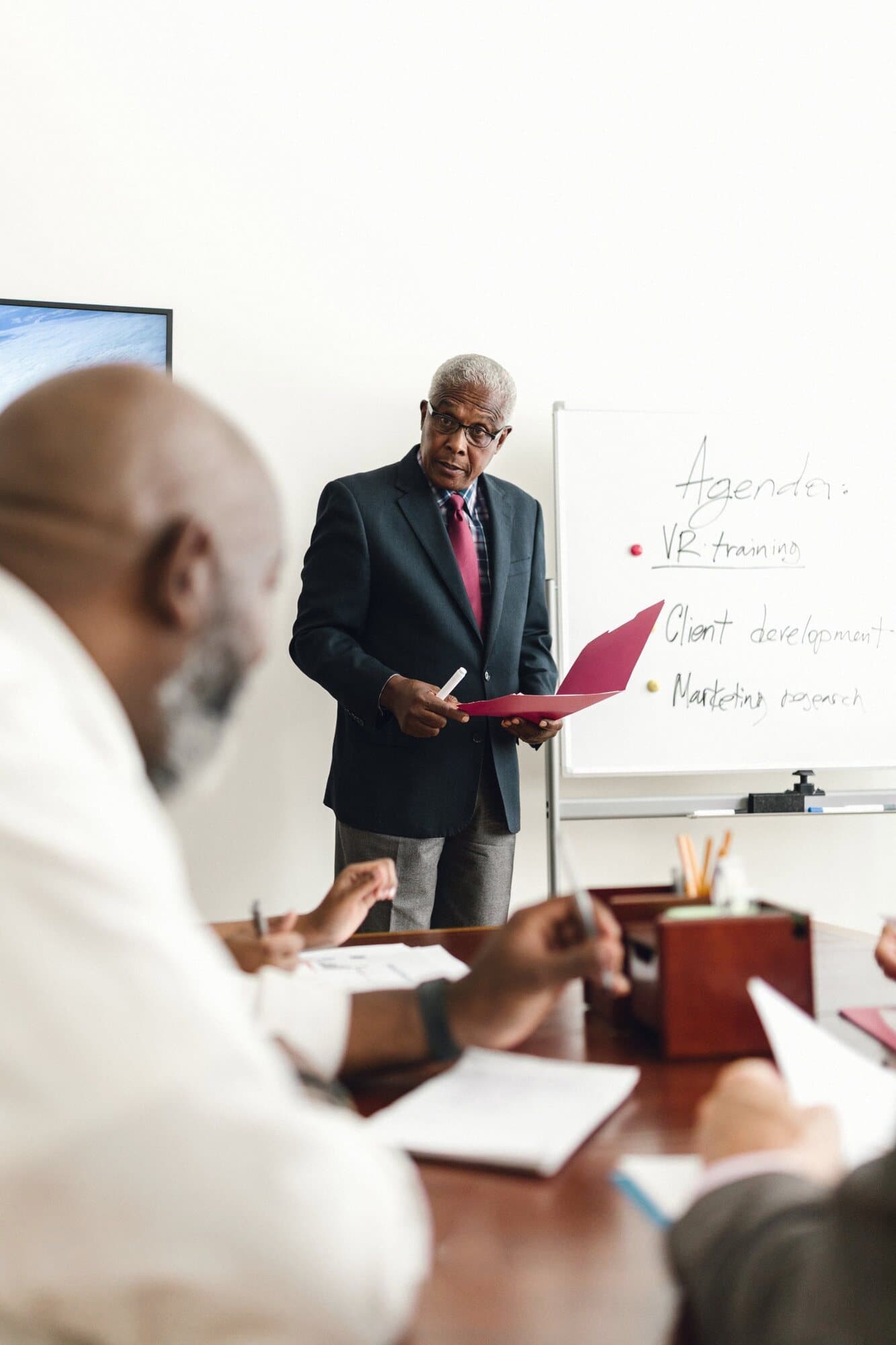 A facilitator standing at the front of a workshop, officials seated around the table.